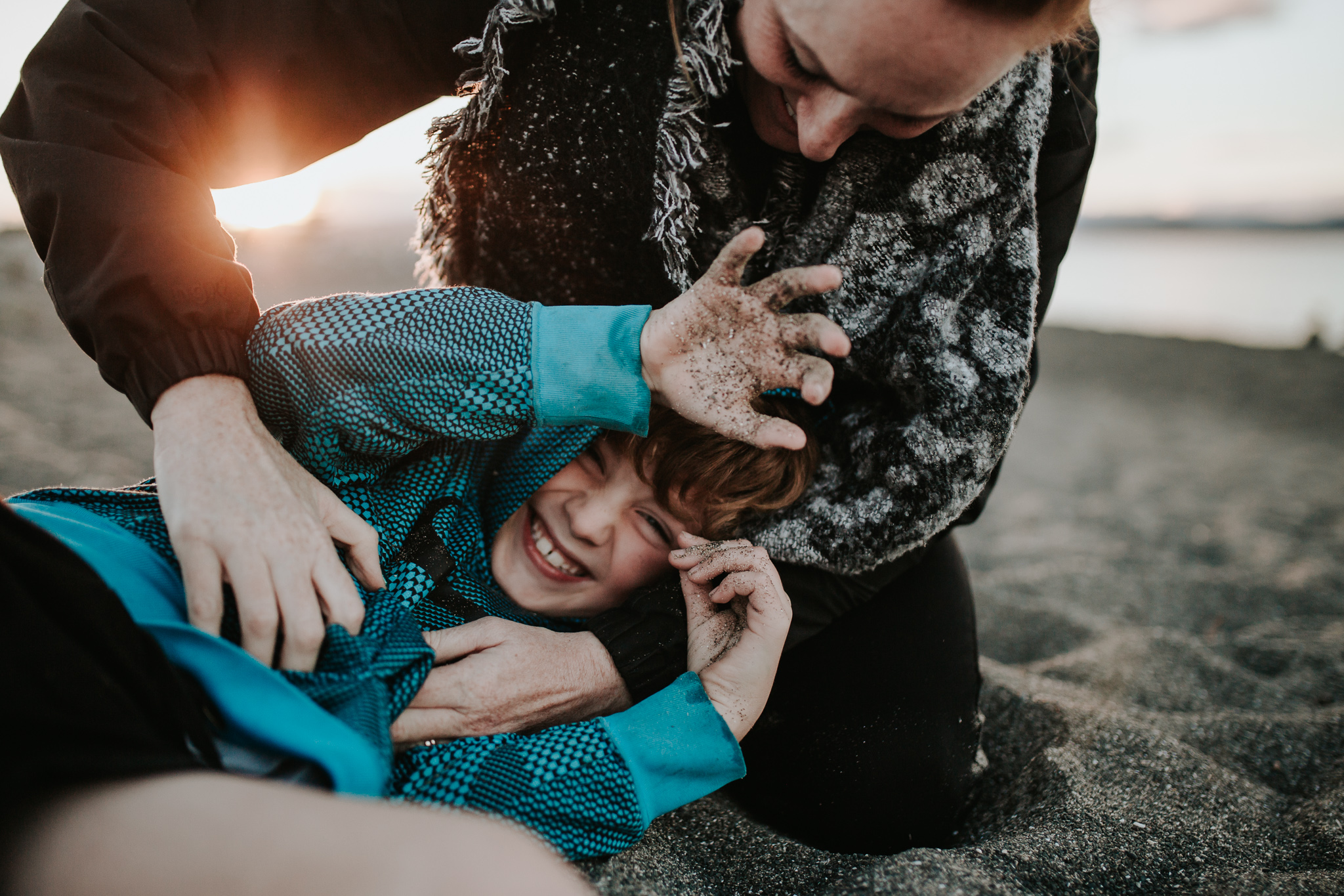 mum tickles son beach sunset