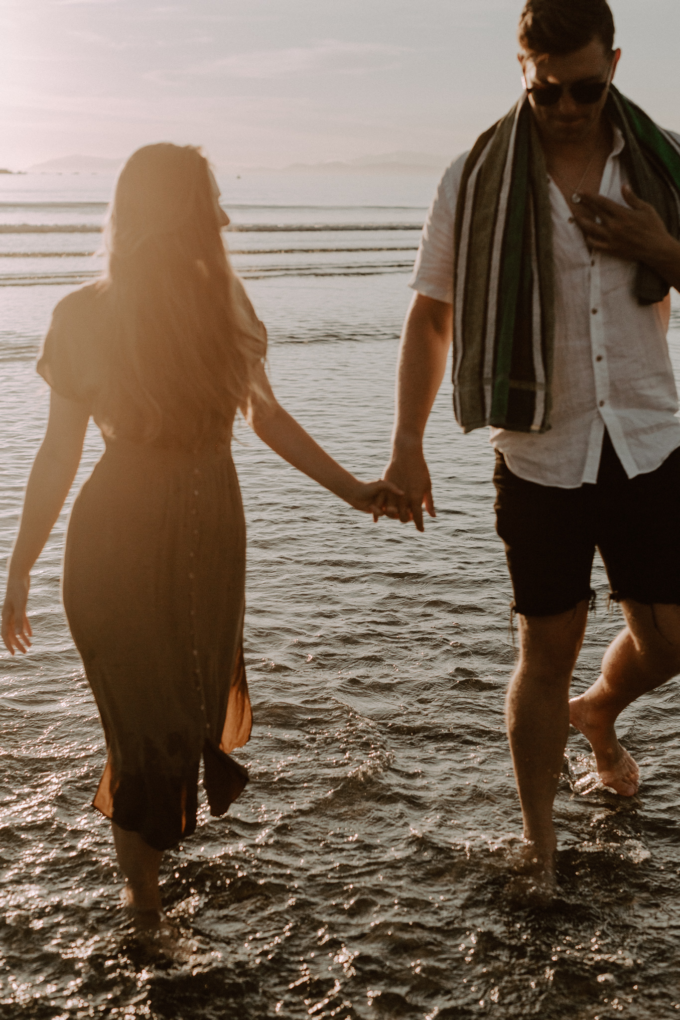 couple hold hands beach sunset