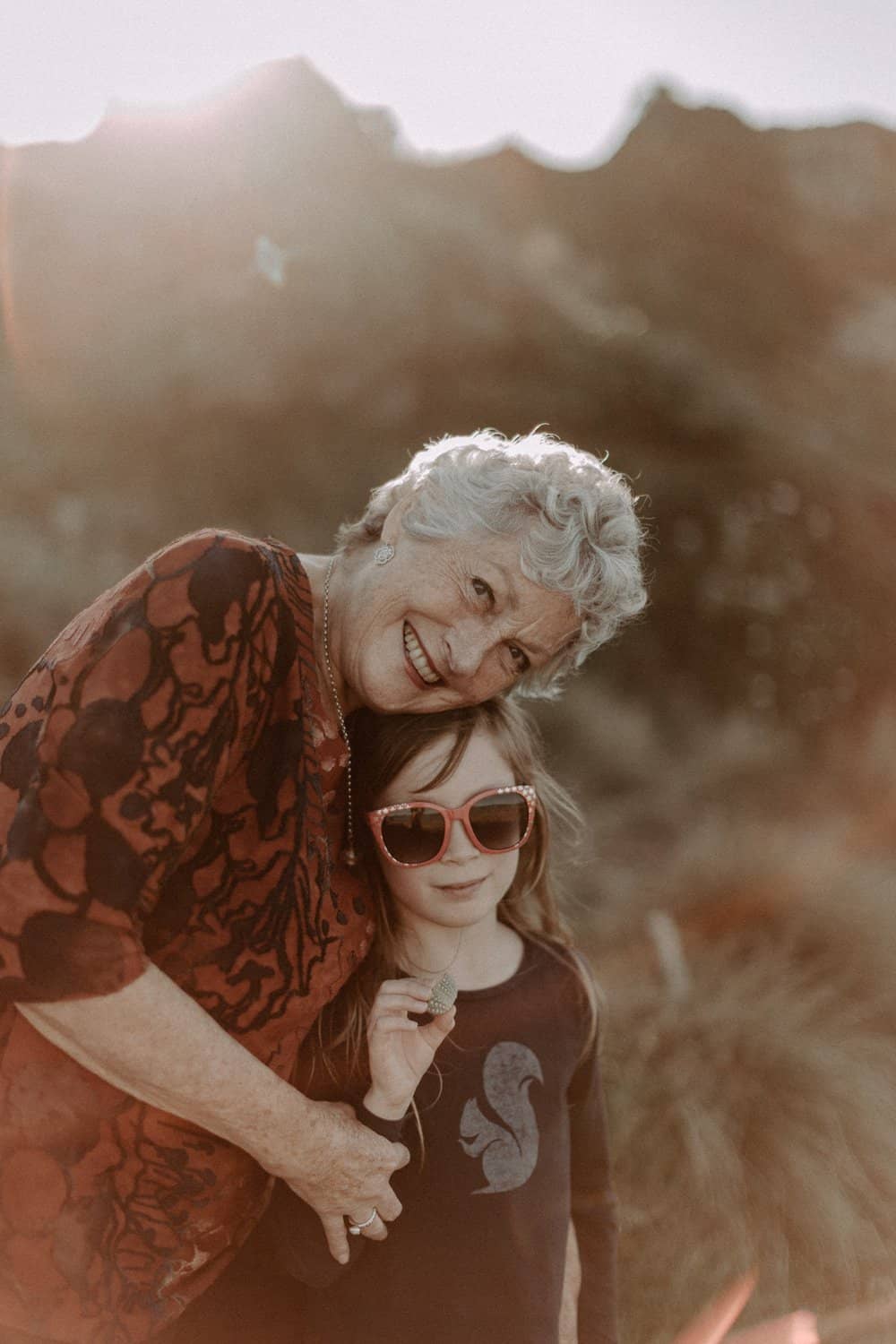 Grandma hugs little girl sunset