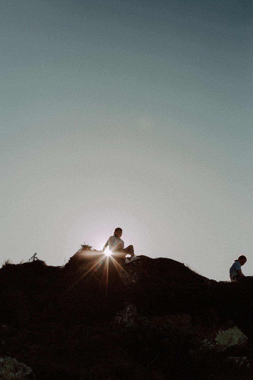 family sits on top of a hill sunset